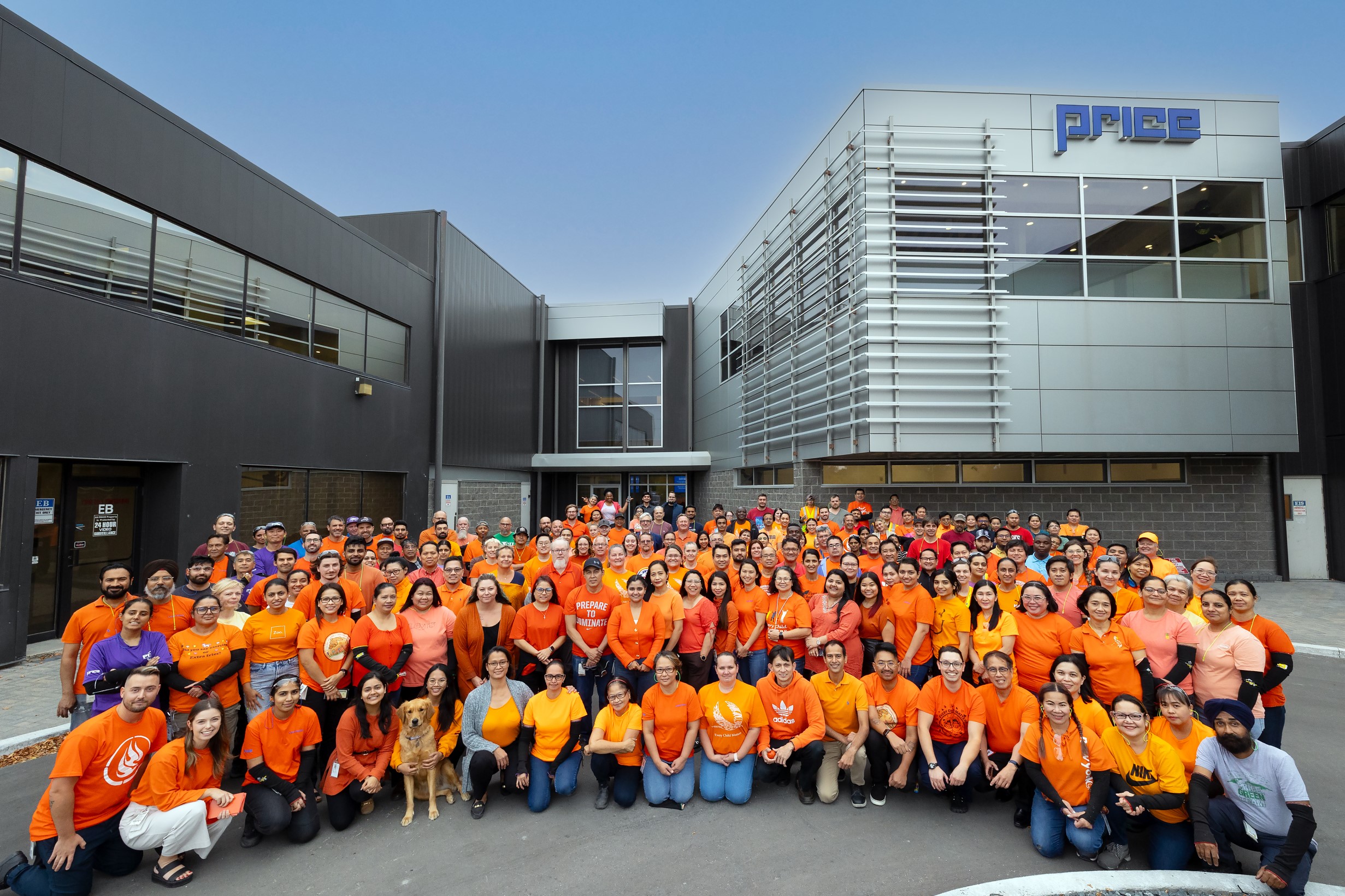 The Price team, wearing orange shirts, outside the Price building