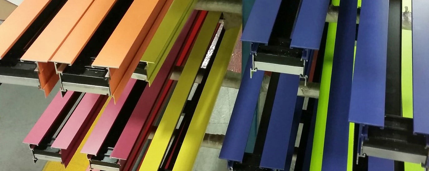 A stack of linear slot diffusers in various bright colors on a rack in a factory
