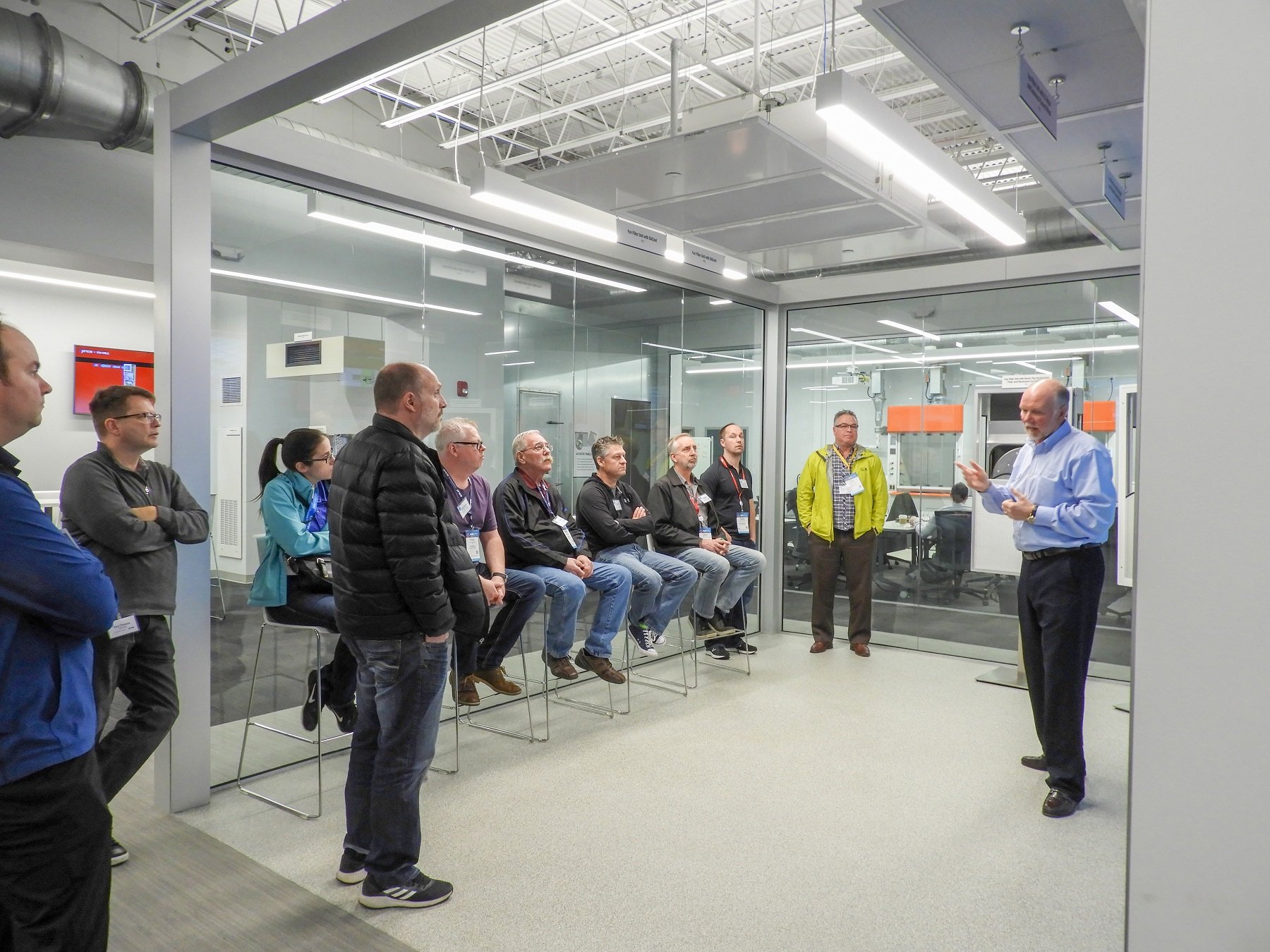 A group of visitors listen to a presentation in the Critical Environments demonstration area