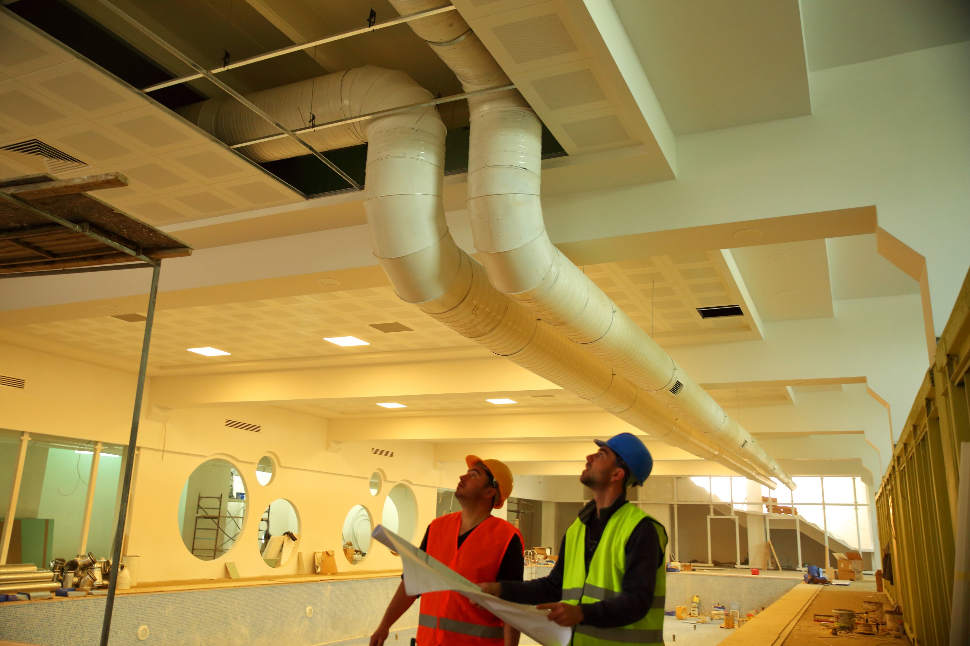 Two HVAC workers inspect ductwork