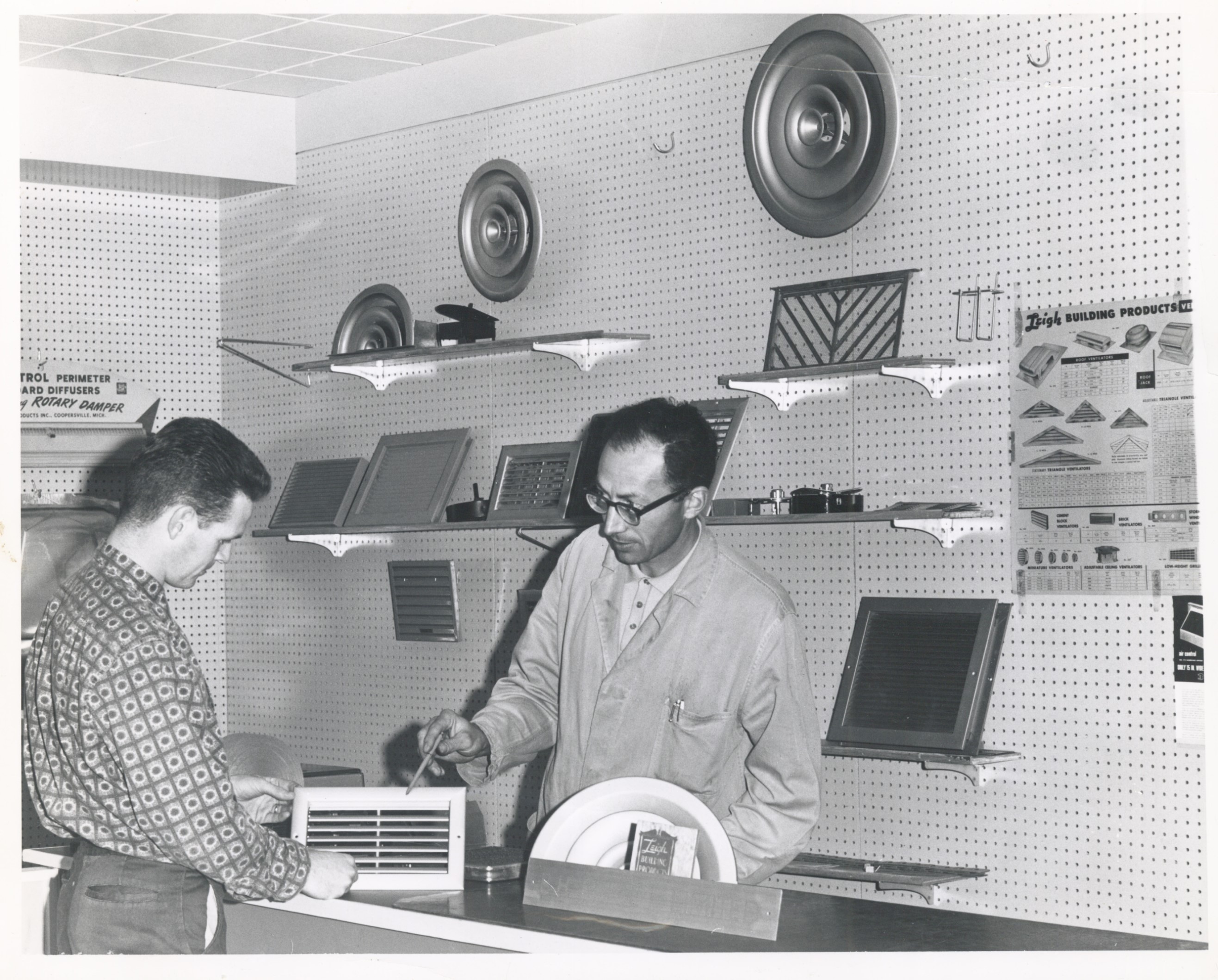 A sales associate showing a grille to a customer at a sales counter