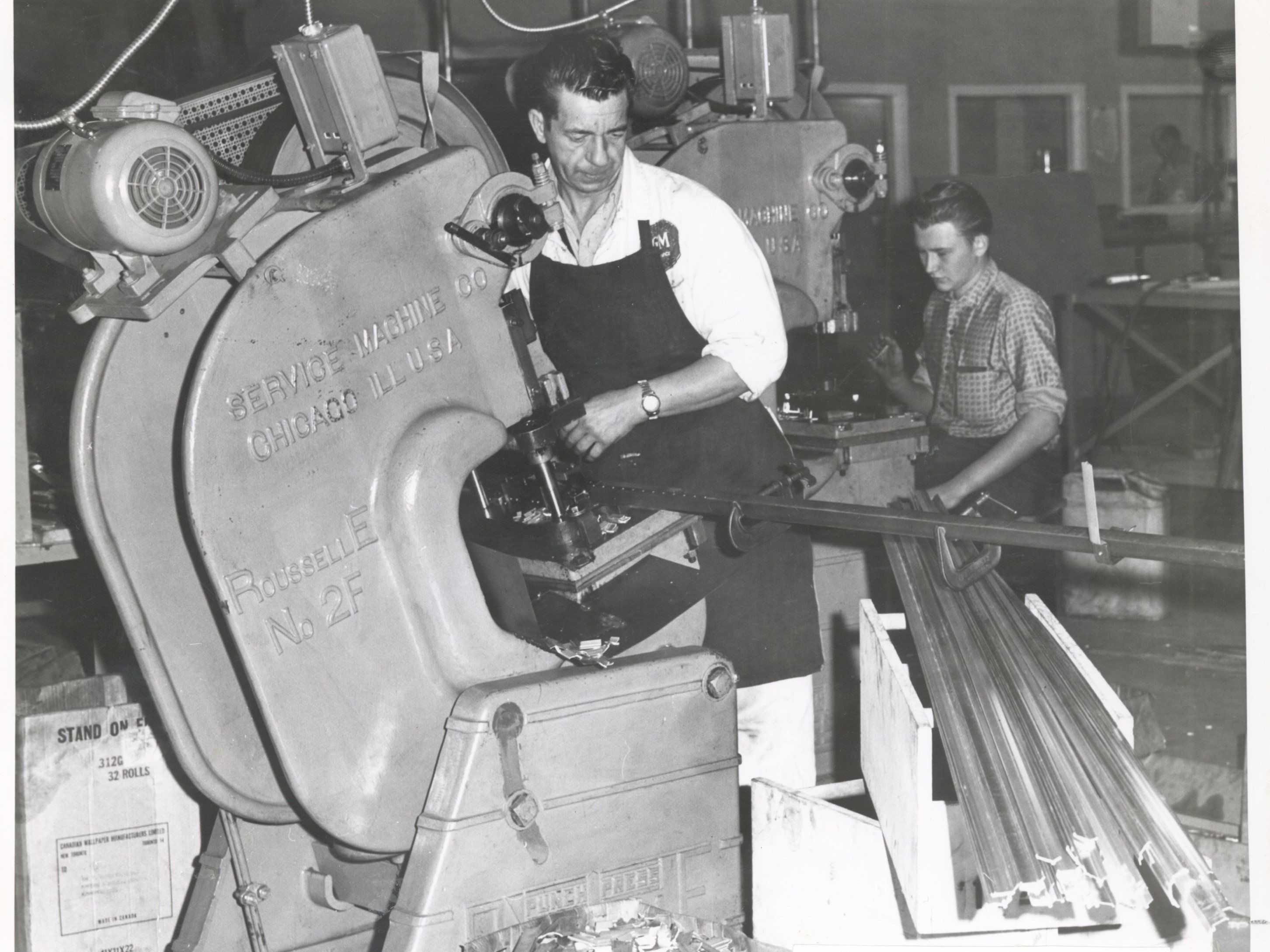 Two men working machinery in a factory
